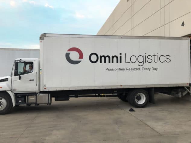 Driver in Omni ground freight truck at warehouse dock in Dallas Texas