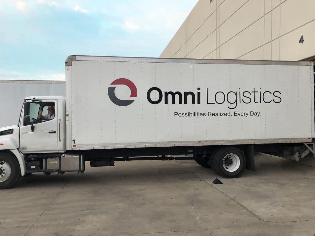 Driver in Omni ground freight truck at warehouse dock in Dallas Texas