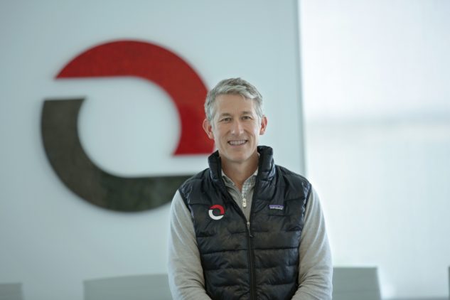 Omni Logistics CEO JJ Schickel headshot standing in logistics boardroom with large Omni logo at Dallas, Texas headquarters